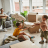 Children play with pillows in a room filled with moving boxes while an adult begins unpacking, capturing the excitement and transition of moving into a new home during a military PCS.