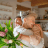 Two people embrace in a cozy kitchen while one holds a bouquet of fresh flowers, reflecting the loved ones who may one day become a life insurance beneficiary.