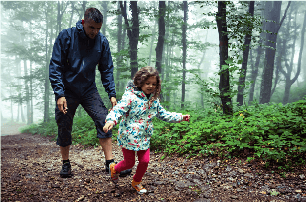 Father and child hiking together on a forest trail, representing life transitions and maintaining protection for families after military service.