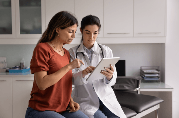 A patient and healthcare provider review information on a tablet during an office visit, reflecting the importance of understanding TRICARE coverage and available supplement options.