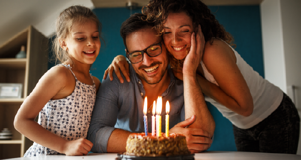 A family of three celebrates a birthday together, illustrating how life stages and age can influence life insurance needs and rates. 