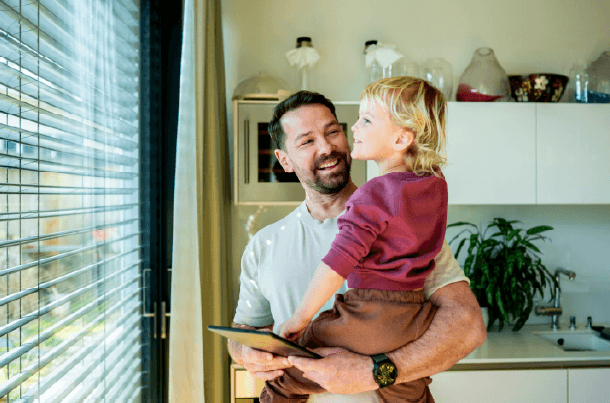 Father holding his young child in their home, illustrating the family and financial responsibilities life insurance can help protect.
