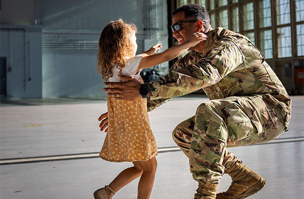 Military father reunites with his young daughter in a hangar-symbolizing the deeper protection now offered by life insurance with no war clause.