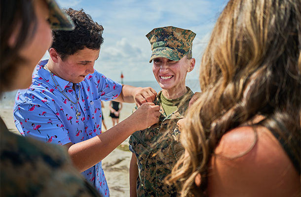 Marine smiles as a family member pins her new rank insignia during a beachside promotion ceremony, marking a milestone moment to reassess life insurance needs.