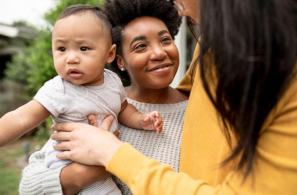 Smiling parents hold their adopted baby close-representing the importance of life insurance in protecting military families through every stage of adoption