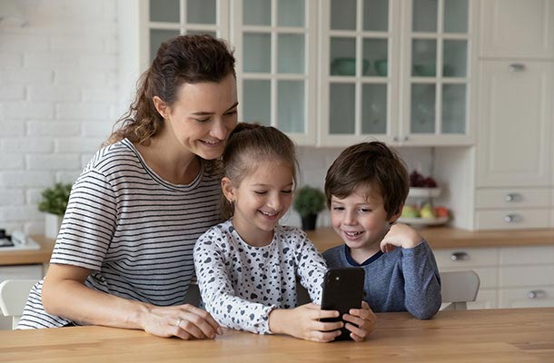 Military parent with two children smiling at a phone-highlighting how PCS moves put families at higher risk of identity theft and cyber threats.