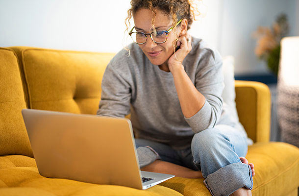 Woman securely managing personal accounts on a laptop at home, illustrating safe online habits for servicemembers.