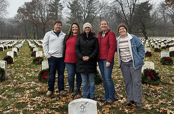 USBA team members pause for a photo after helping lay wreaths at a national cemetery as part of Wreaths Across America, paying tribute to those who served.